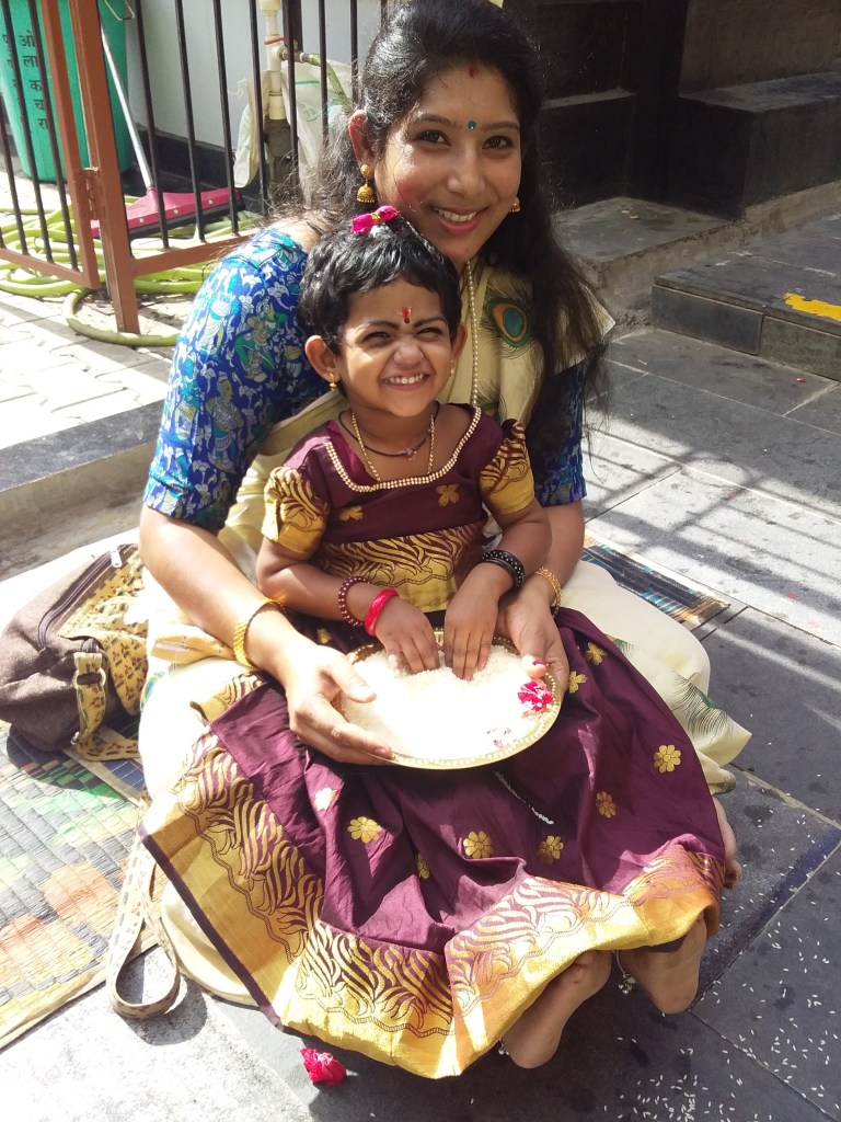A picture of Rithika writing in rice during her Vidyarambham. Image Credit: Pradeep Mohandas